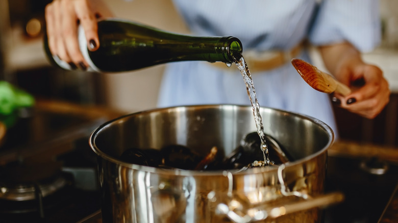 pouring wine into pot on the stove